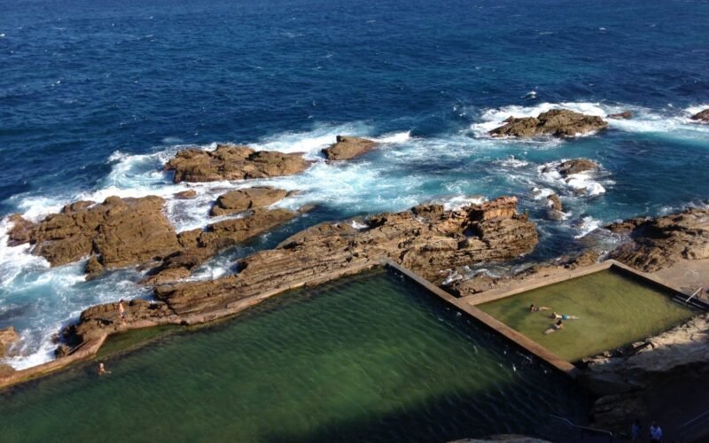 Swimmers in the Blue Pool beneath the Bermagui headland cliffs